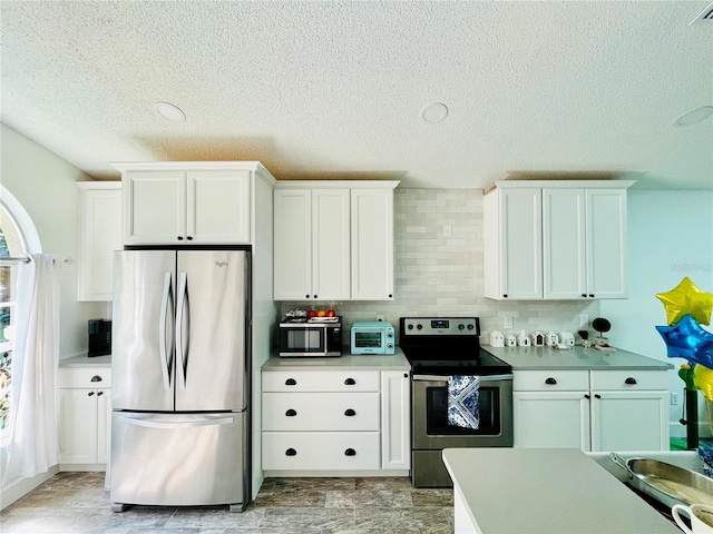 kitchen with appliances with stainless steel finishes, backsplash, white cabinetry, and a textured ceiling