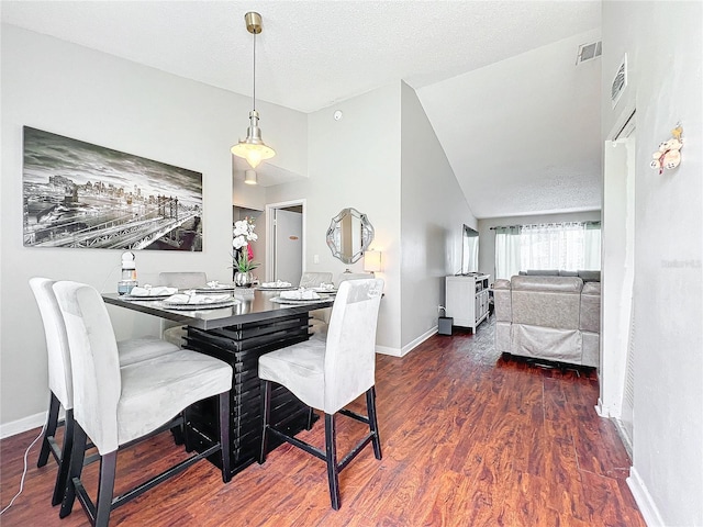 dining room with a textured ceiling, high vaulted ceiling, and dark wood-type flooring