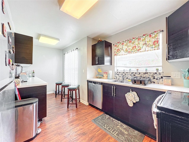 kitchen with dark brown cabinets, backsplash, light hardwood / wood-style floors, dishwasher, and range with electric cooktop