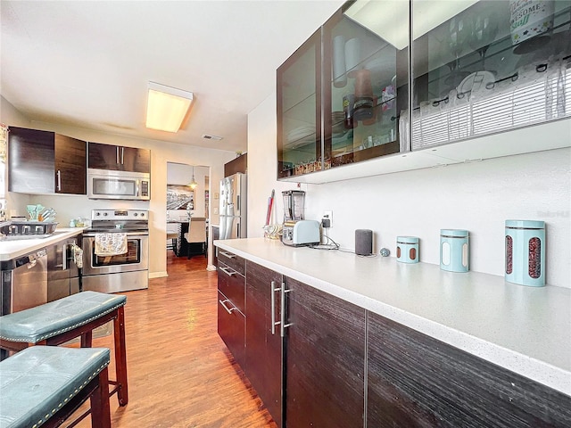 kitchen featuring light hardwood / wood-style floors, stainless steel appliances, dark brown cabinetry, and sink