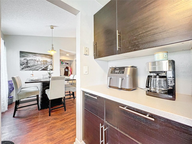 kitchen with decorative light fixtures, hardwood / wood-style floors, dark brown cabinetry, a textured ceiling, and lofted ceiling