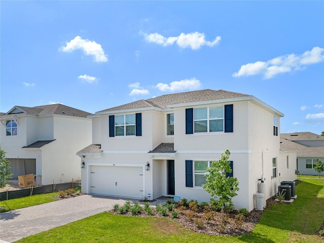 view of front of property with central AC, a garage, and a front lawn