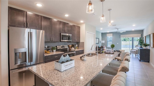 kitchen with appliances with stainless steel finishes, sink, and a center island with sink