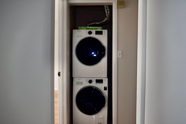 laundry area featuring stacked washer and dryer and wood-type flooring