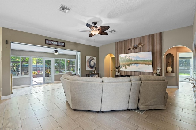 tiled living room with a textured ceiling and ceiling fan