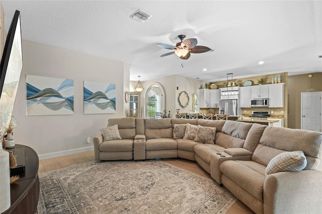 living room with ceiling fan, hardwood / wood-style flooring, and a textured ceiling