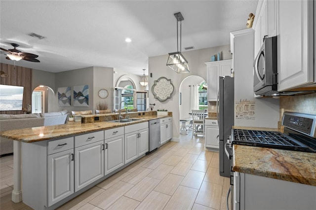 kitchen featuring appliances with stainless steel finishes, ceiling fan, white cabinetry, sink, and pendant lighting