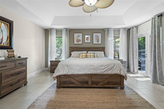 bedroom with a tray ceiling, ceiling fan, and multiple windows