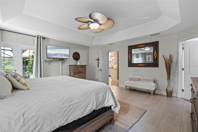 bedroom with access to outside, ceiling fan, french doors, and a tray ceiling