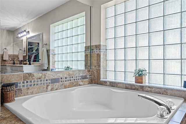 bathroom with a relaxing tiled bath and a healthy amount of sunlight