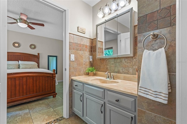 bathroom with tile walls, vanity, tile flooring, ceiling fan, and a textured ceiling