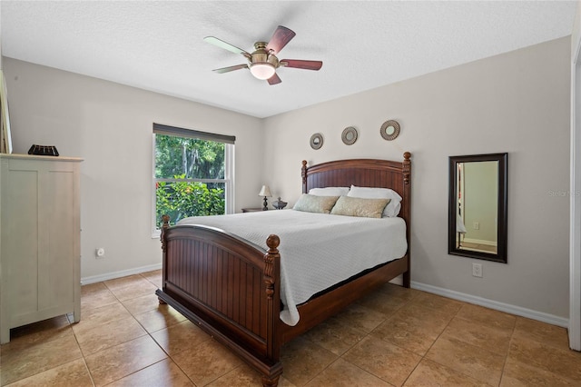 bedroom with ceiling fan, light tile flooring, and a textured ceiling