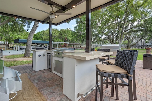 view of terrace featuring exterior kitchen, ceiling fan, and a grill