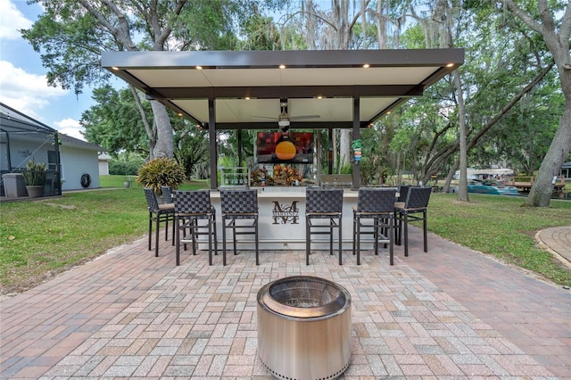 view of patio featuring a fire pit, ceiling fan, and a bar