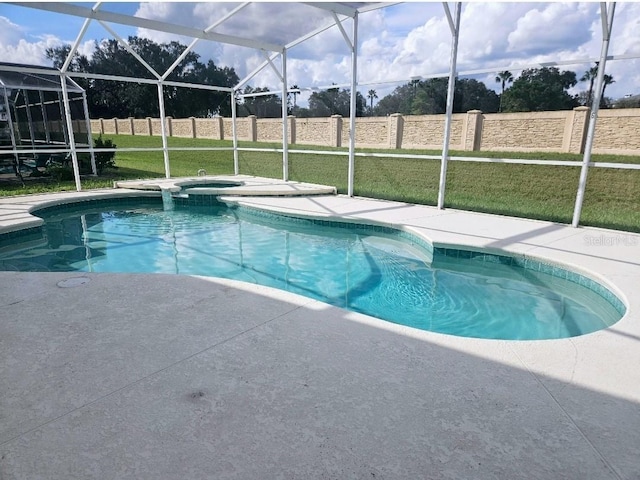 view of pool with a lanai, a lawn, a patio, and an in ground hot tub