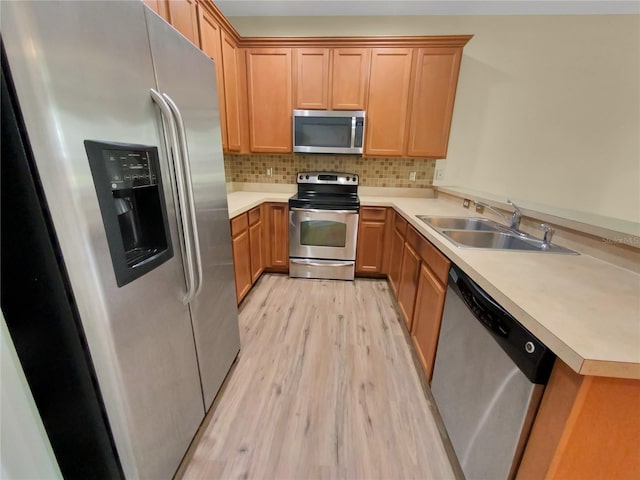 kitchen with backsplash, kitchen peninsula, appliances with stainless steel finishes, sink, and light hardwood / wood-style floors