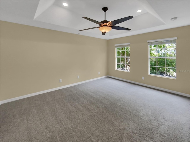 carpeted spare room featuring ceiling fan and a raised ceiling