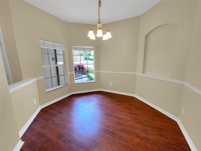 spare room with hardwood / wood-style floors and a notable chandelier