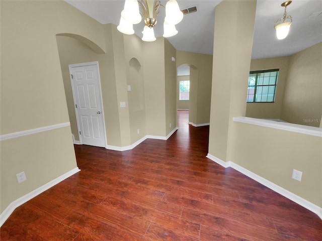 spare room with dark hardwood / wood-style flooring and a chandelier