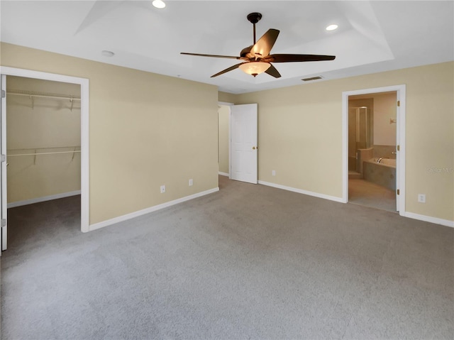 unfurnished bedroom with a spacious closet, ensuite bath, ceiling fan, carpet flooring, and a closet