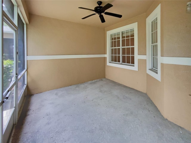 unfurnished sunroom with ceiling fan