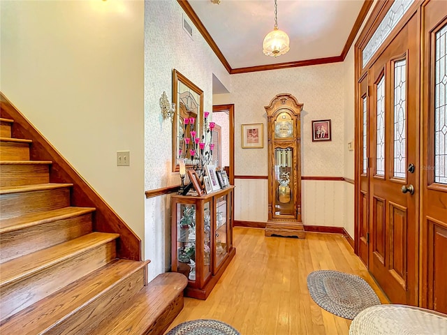 entryway with ornamental molding and hardwood / wood-style floors