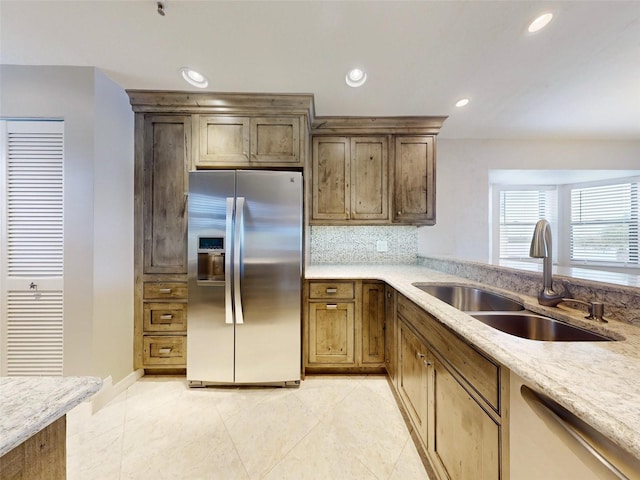 kitchen with tasteful backsplash, light stone counters, stainless steel appliances, sink, and light tile patterned floors