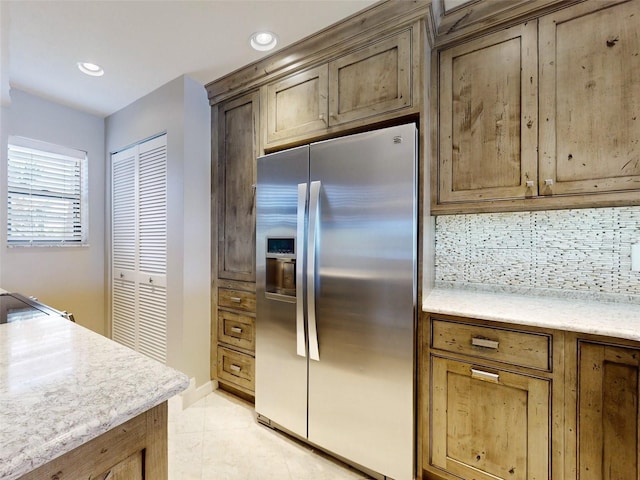 kitchen featuring stainless steel fridge with ice dispenser, light tile patterned floors, and tasteful backsplash