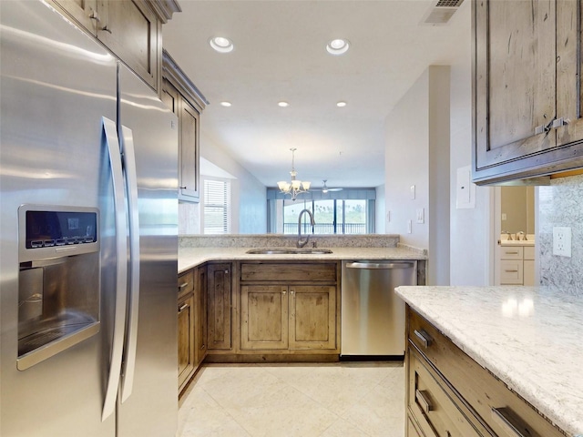 kitchen featuring sink, stainless steel appliances, tasteful backsplash, pendant lighting, and a chandelier