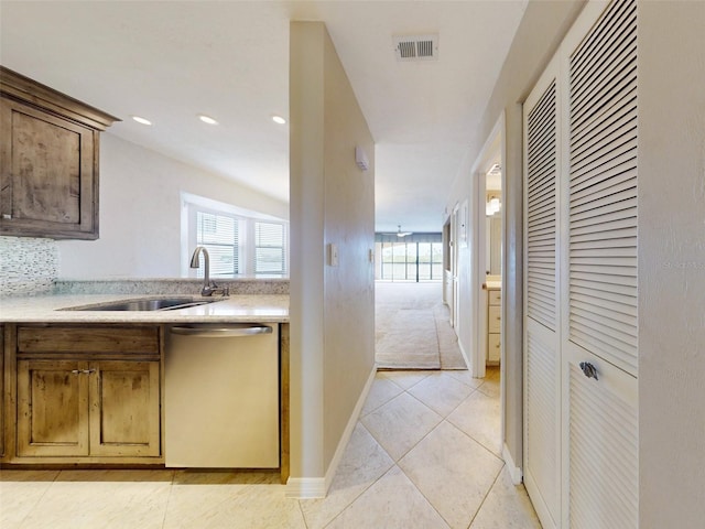 kitchen featuring sink, stainless steel dishwasher, a wealth of natural light, and light tile patterned flooring