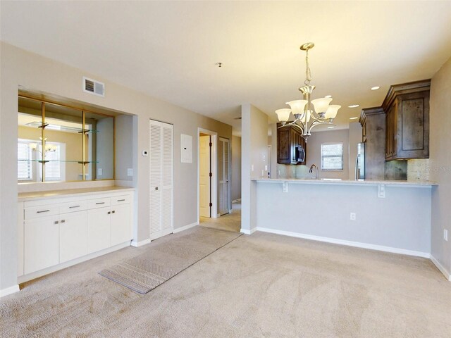 kitchen featuring kitchen peninsula, dark brown cabinets, stainless steel appliances, light colored carpet, and white cabinets