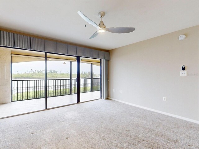 spare room featuring light carpet, a water view, and ceiling fan