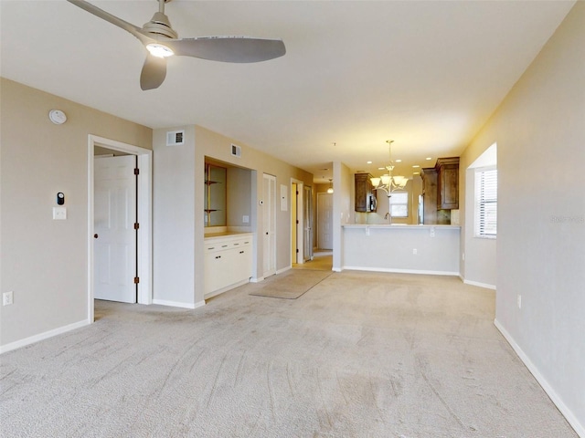 unfurnished living room featuring ceiling fan with notable chandelier and light carpet