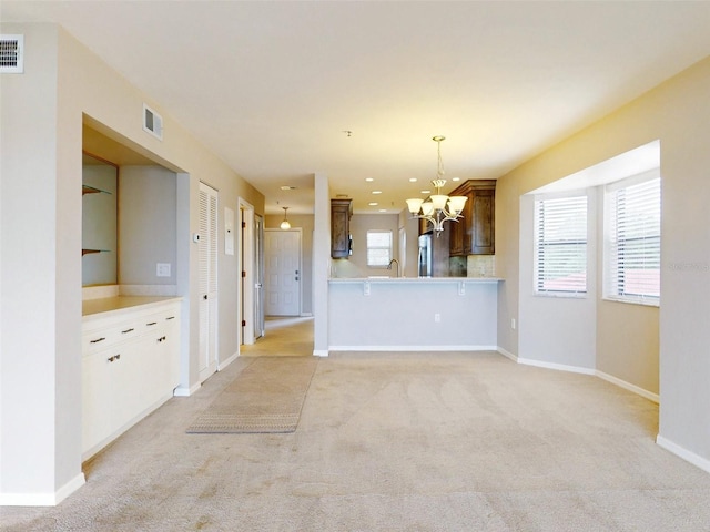 interior space with kitchen peninsula, light carpet, decorative light fixtures, and decorative backsplash