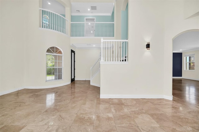 foyer with crown molding, tile flooring, and a towering ceiling