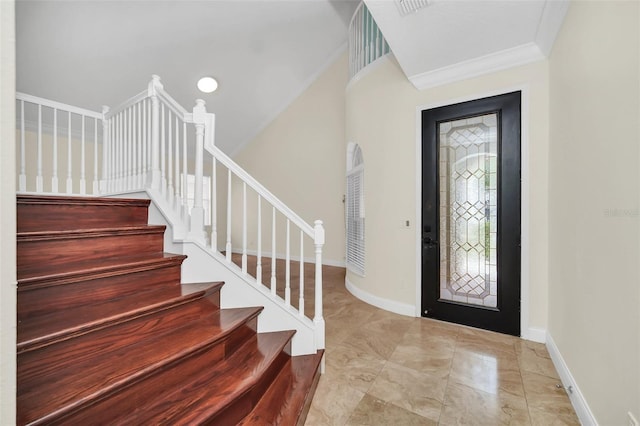 entrance foyer with crown molding and light tile floors