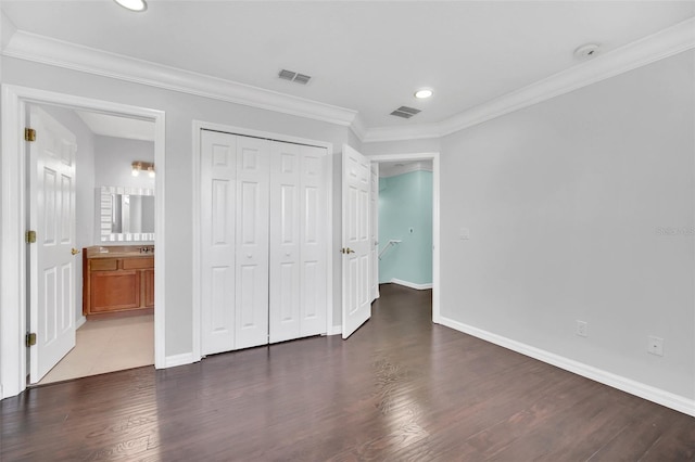 unfurnished bedroom featuring ornamental molding, ensuite bath, and dark tile floors