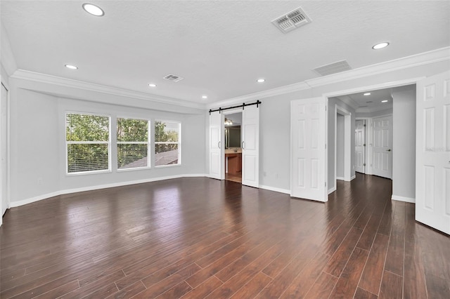 unfurnished living room featuring a textured ceiling, dark wood-type flooring, crown molding, and a barn door