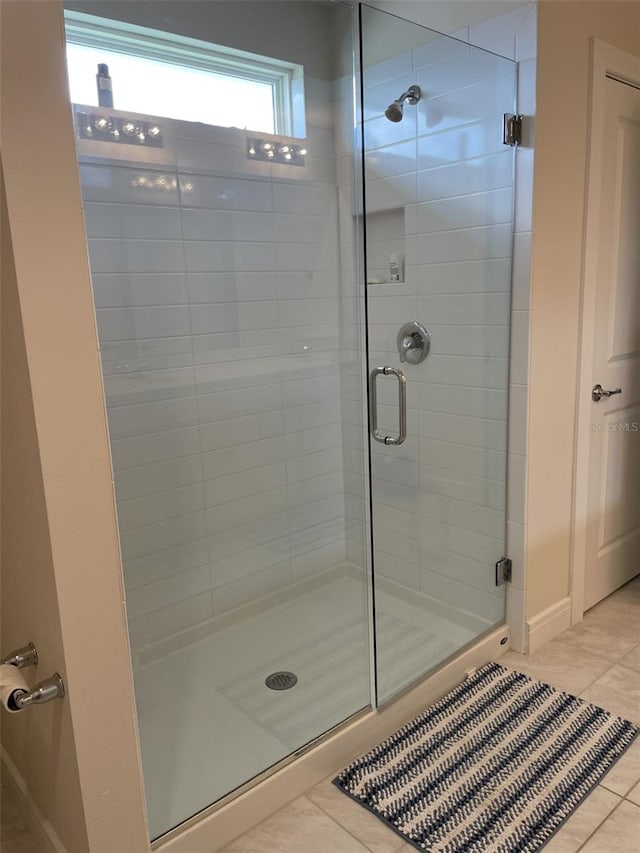 bathroom with a shower with shower door and tile patterned floors