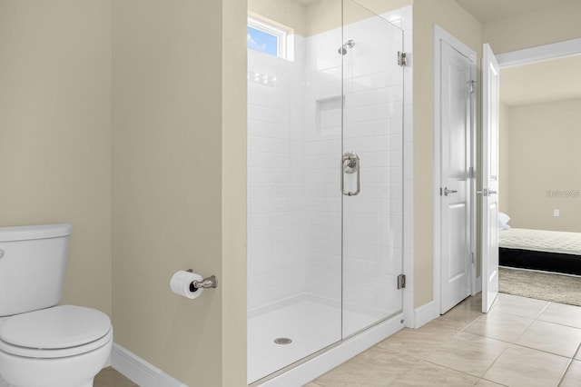 bathroom featuring tile patterned flooring, a shower with door, and toilet