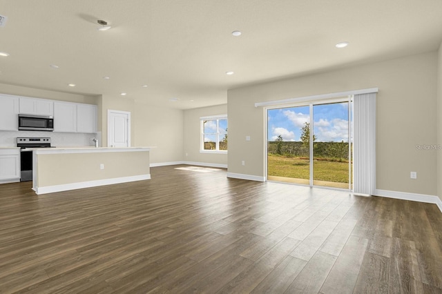 unfurnished living room with dark hardwood / wood-style floors and a healthy amount of sunlight