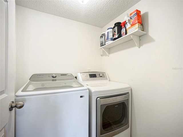 clothes washing area with washing machine and dryer and a textured ceiling