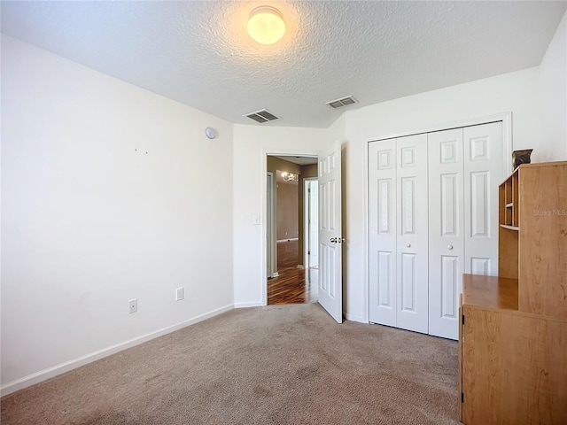 unfurnished bedroom with a closet, light colored carpet, and a textured ceiling