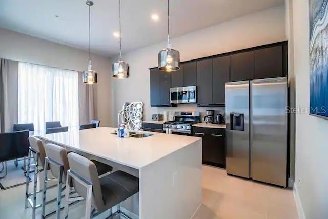 kitchen featuring appliances with stainless steel finishes, sink, a center island with sink, and pendant lighting