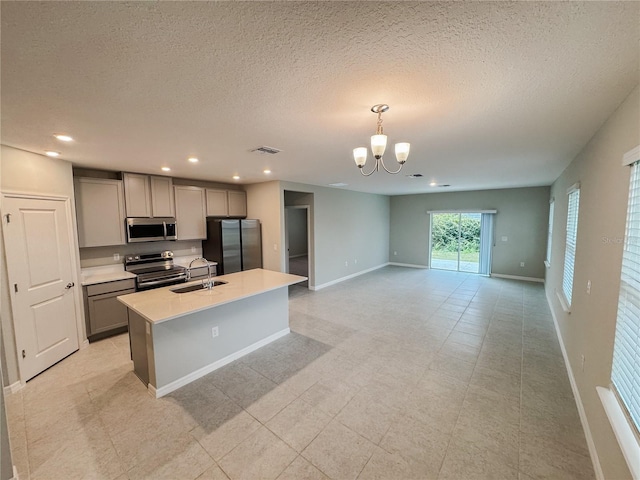 kitchen with pendant lighting, an inviting chandelier, a center island with sink, gray cabinets, and stainless steel appliances