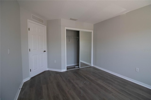 unfurnished bedroom featuring a closet and dark hardwood / wood-style floors