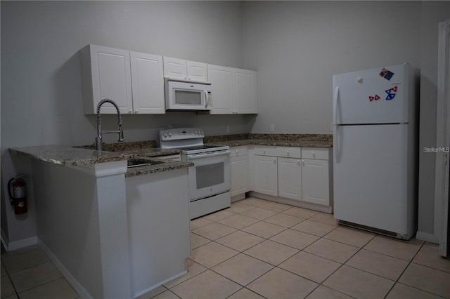 kitchen featuring stone counters, white cabinets, white appliances, and light tile floors