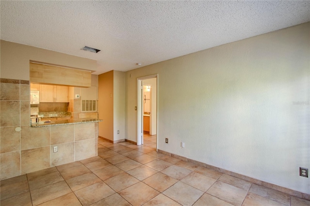 unfurnished room with light tile patterned flooring, sink, and a textured ceiling