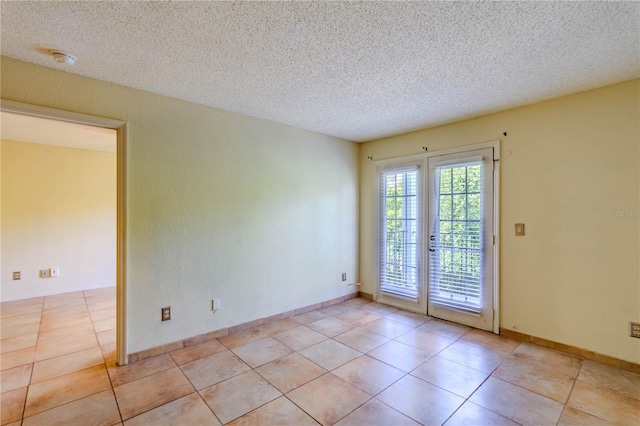 tiled empty room featuring a textured ceiling