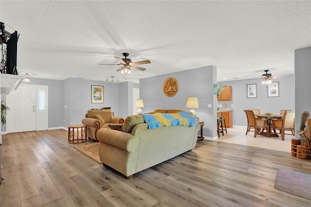 living room with wood-type flooring, a textured ceiling, and ceiling fan